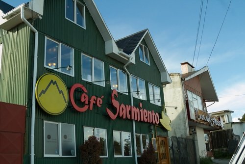 Café Sarmiento in Punta Arenas, Chile — a green wooden building with large windows and a red sign, located near the Mirador Cerro de la Cruz viewpoint.