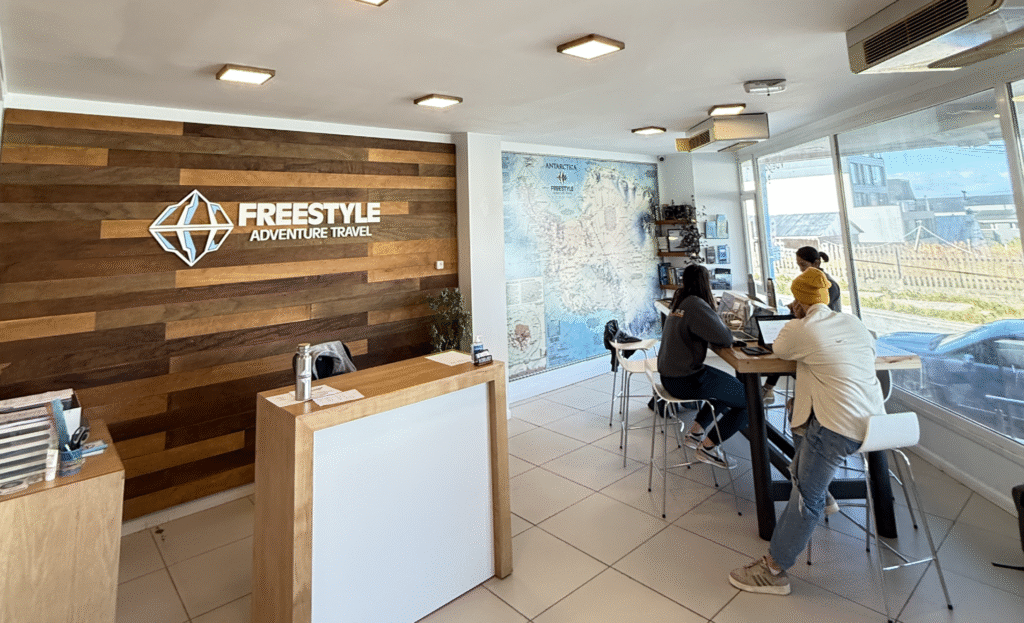 Freestyle Adventure Travel office interior in Ushuaia, with staff assisting travelers and Antarctica map wall display